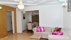 A living room with a sofa, a small wooden table, and a chandelier. - Sterling Lakeview Apartment  (Port Harcourt)