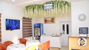 A hotel dining area with tables and chairs, a television, a minibar, and a reception desk. - Sterling Lakeview Apartment  (Port Harcourt)