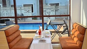 A dining area with a pool view, featuring cushioned seating and a table set for two. - Sterling Lakeview Apartment  (Port Harcourt)