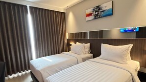Une chambre d’hôtel avec deux lits, un téléviseur à écran plat et une grande fenêtre avec des rideaux.