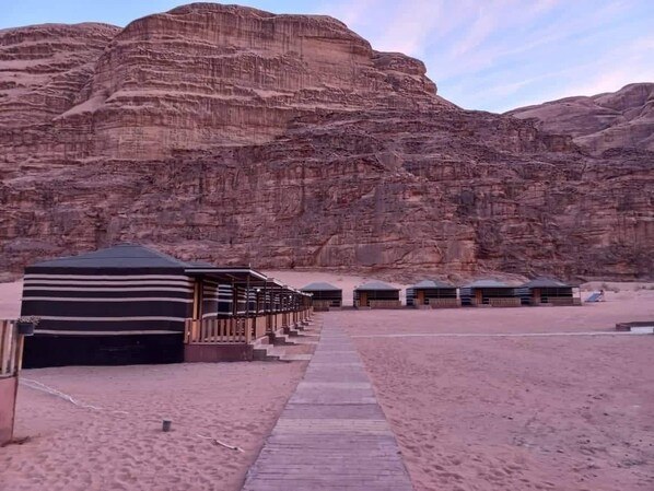 A desert resort with a row of cabins and a large tented area.