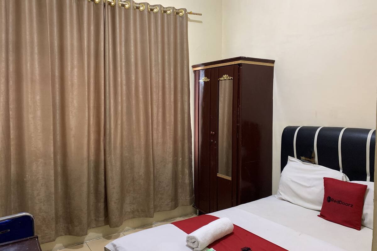 Una camera d'albergo con un letto, un armadio e una tenda.