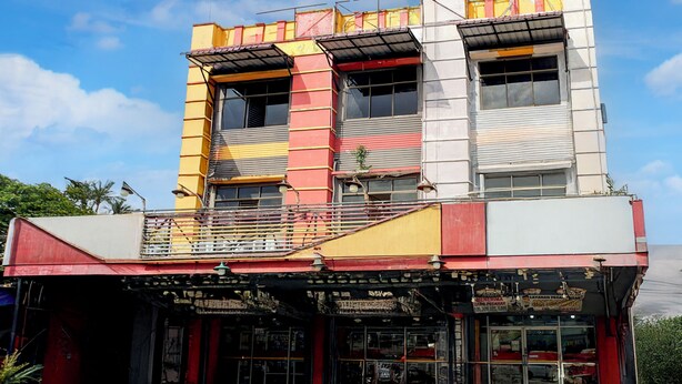 A multi-story building with a commercial ground floor featuring a storefront with glass doors and signage. - Hotel O Medan near Universitas Sumatera Utara formerly Surya Residence (Medan)