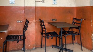 A small, enclosed room with a single table and two chairs, a door with a handle, and two electrical outlets on the wall. - Hotel O Medan near Universitas Sumatera Utara formerly Surya Residence (Medan)