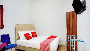 A bedroom with a bed, a chair, a TV, and a wardrobe. - Hotel O Medan near Universitas Sumatera Utara formerly Surya Residence (Medan)