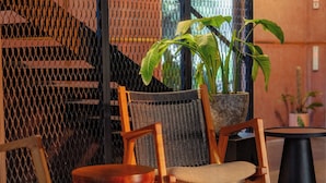 A modern indoor space with a wooden chair, a round table, and a potted plant. - TERRATONE BOUTIQUE BUSINESS HOTEL (Kollam)