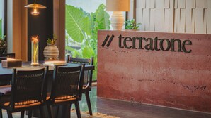 A reception desk with a sign reading "Terratone" and a modern interior with a dining area. - TERRATONE BOUTIQUE BUSINESS HOTEL (Kollam)