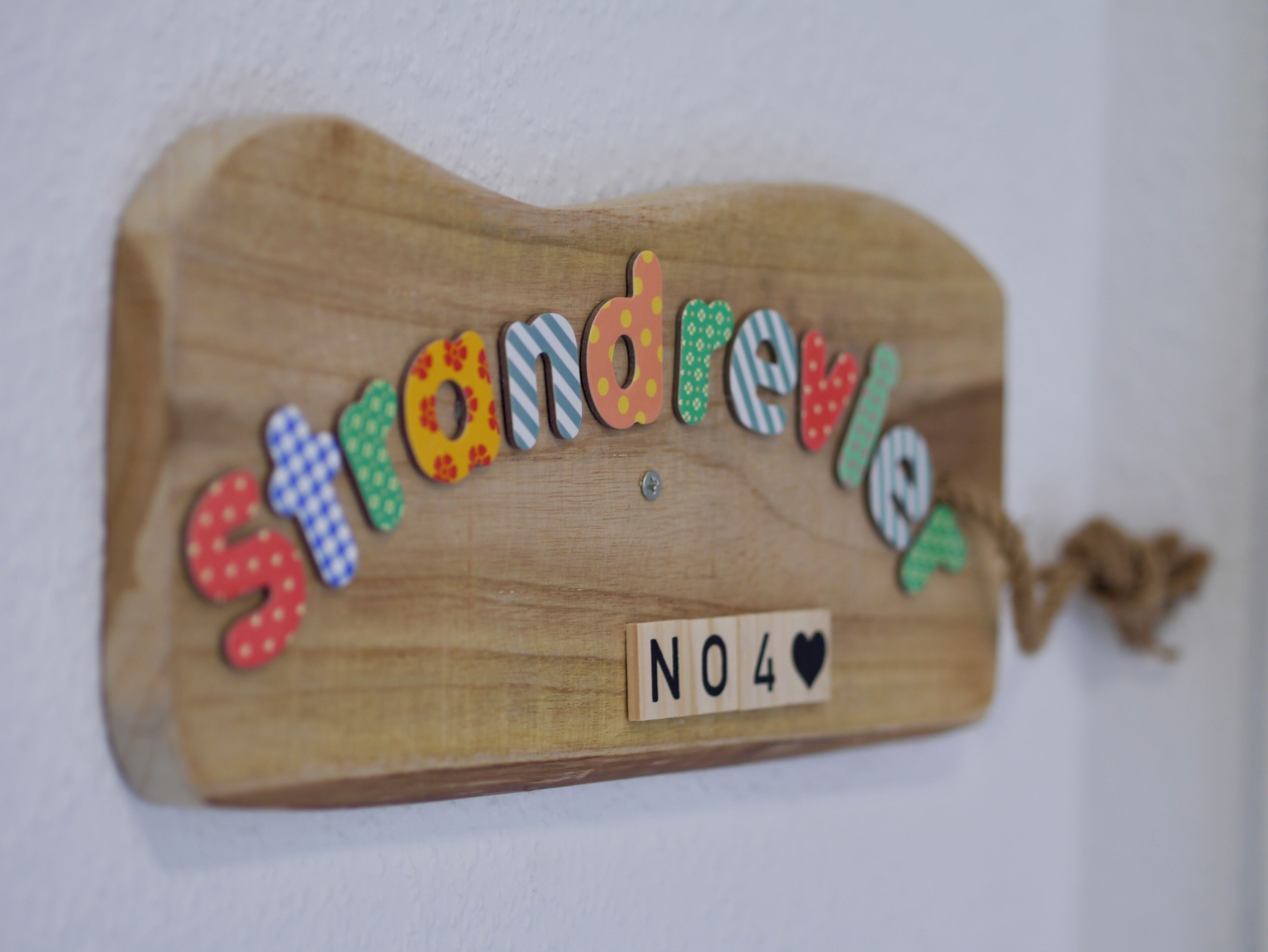 Un letrero de madera con el nombre 'Strandreier' y un símbolo de corazón, indicando una posible ubicación o establecimiento.