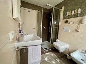 Une salle de bain équipée d’une douche, de toilettes, d’un lavabo et d’un porte-serviettes.