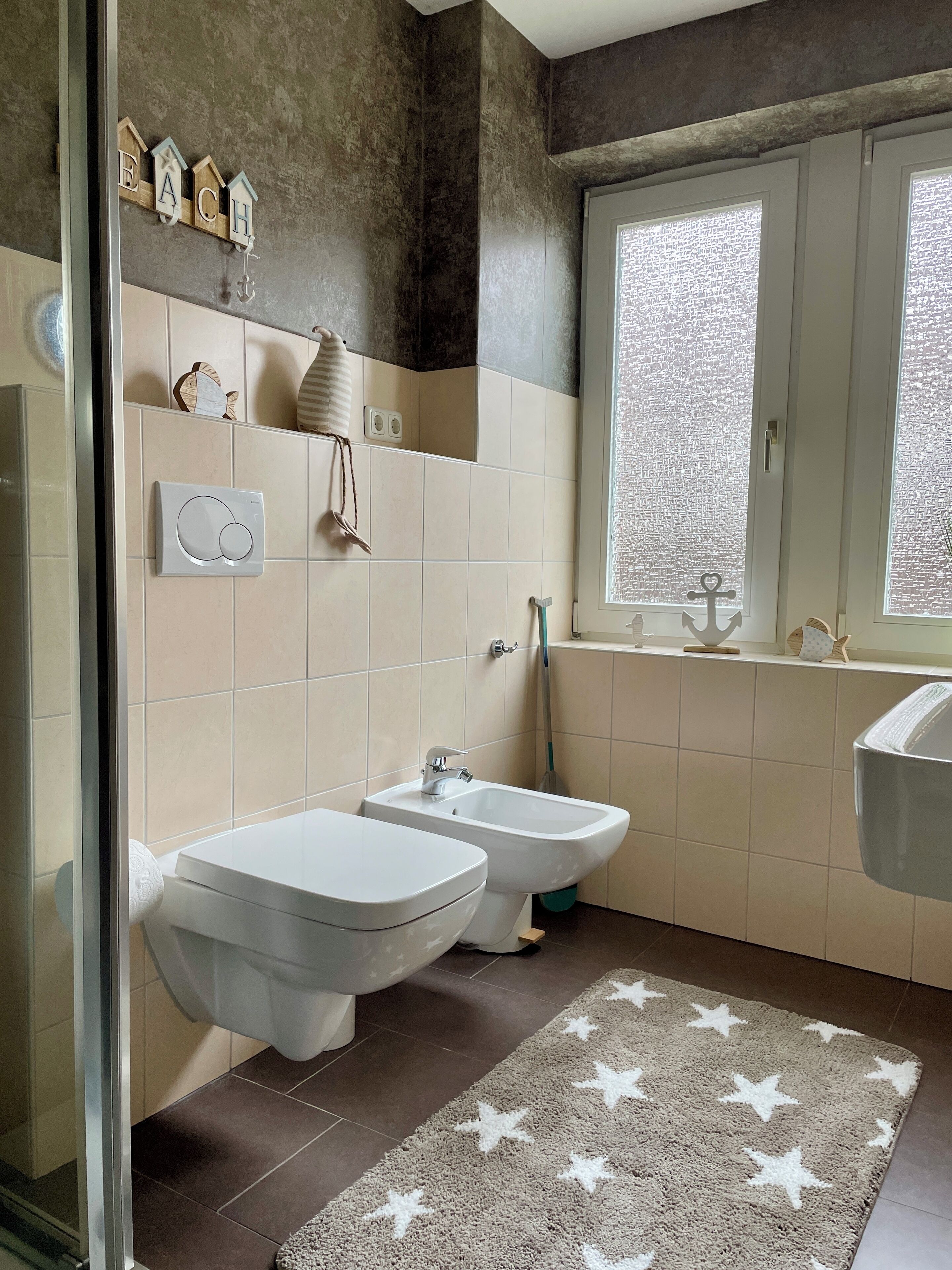 A modern bathroom with two sinks, a window, and a star-patterned rug.