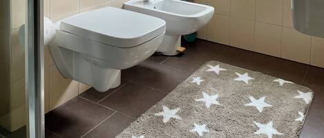A modern bathroom with two sinks, a window, and a star-patterned rug.