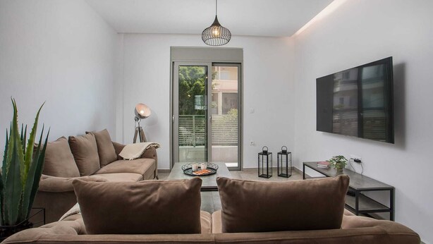 Una sala de estar moderna con un sofá, una mesa de centro, una lámpara de pie, un televisor montado en la pared y vistas a través de un ventanal.