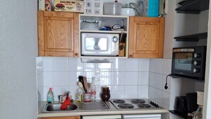A compact kitchen with wooden cabinets, a microwave, a stove, and a dishwasher. - Comfortable 2-BR Apt at the Foot of the Slopes (Saint-François-Longchamp)