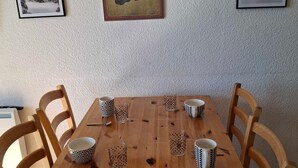 A wooden dining table with four chairs, six patterned cups, and two glasses. - Comfortable 2-BR Apt at the Foot of the Slopes (Saint-François-Longchamp)