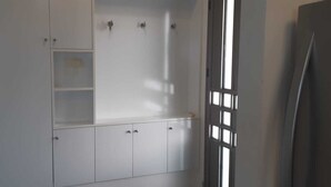Una habitación con un armario blanco, un teléfono y una ventana con persianas.
