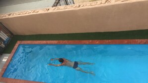 Una piscina rectangular con borde de azulejos y una persona nadando.
