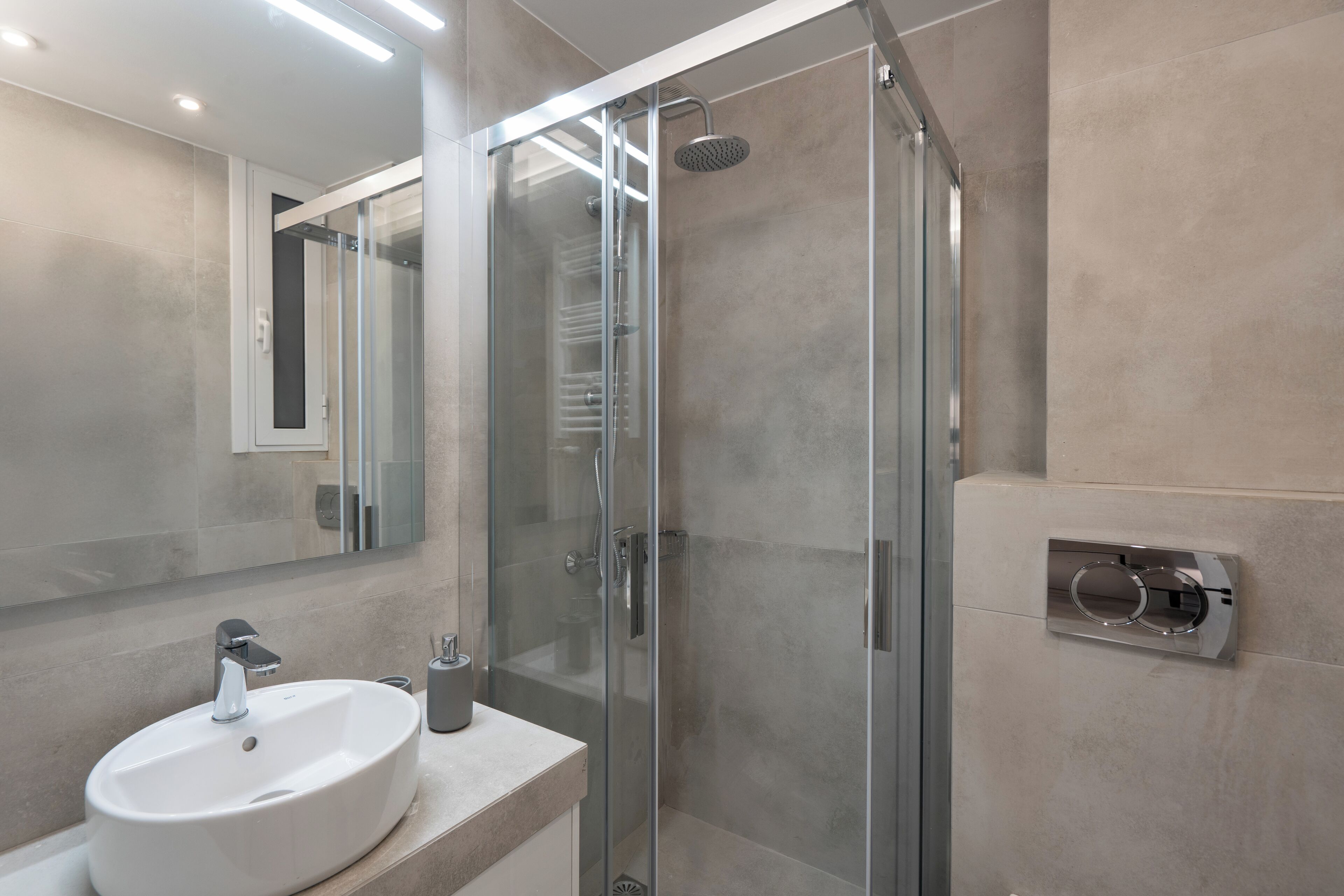 Une salle de bain moderne avec une douche à parois de verre, un lavabo blanc et un grand miroir.