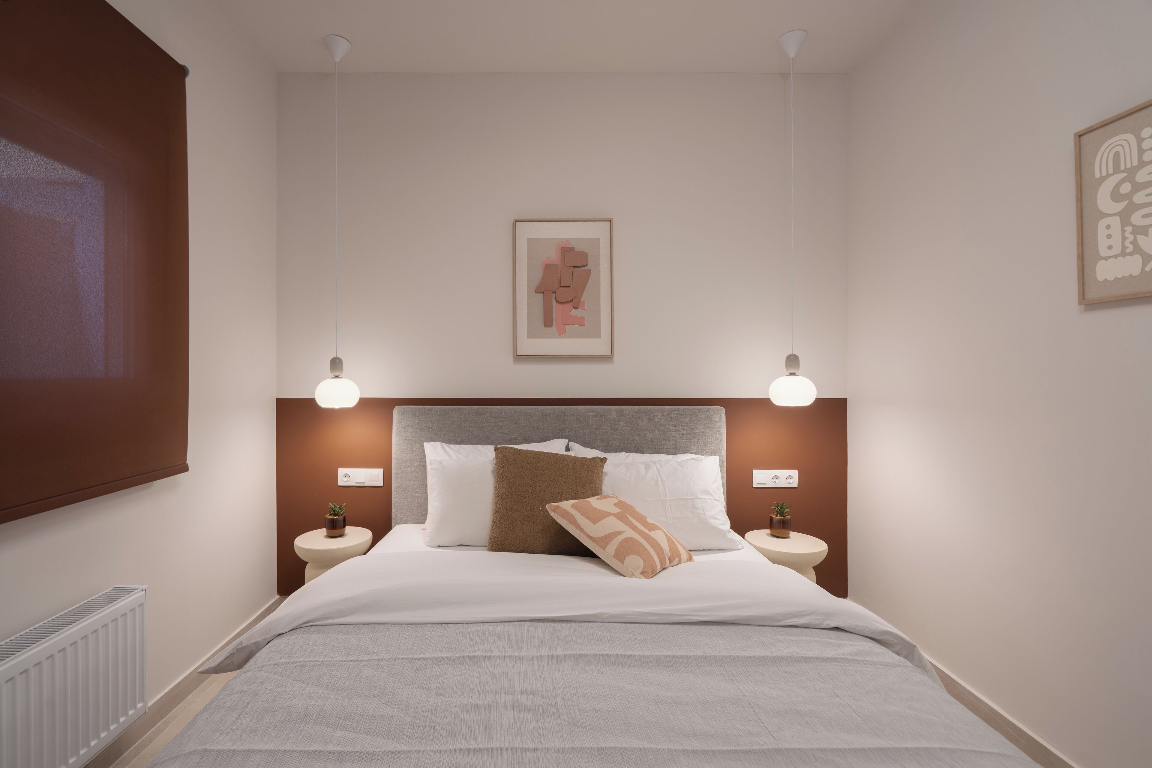 A neatly arranged bedroom with a bed, two bedside tables, a headboard, and wall-mounted lighting.