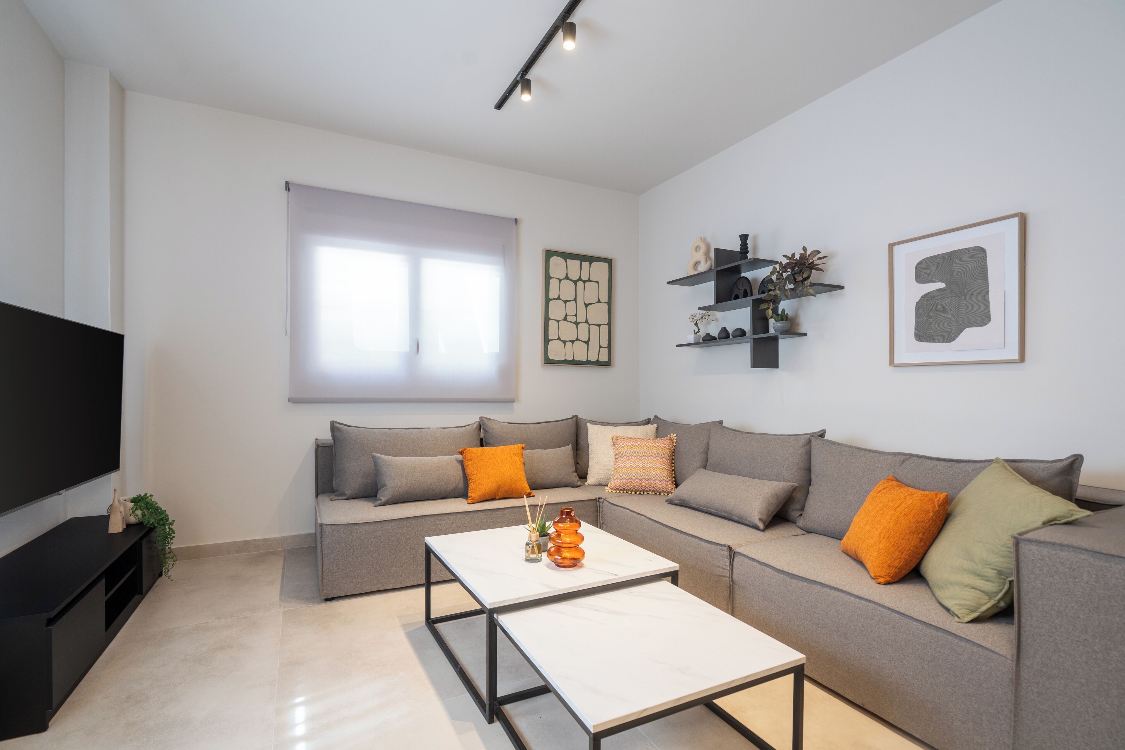 A modern living room with a grey sofa, a white coffee table, and a flat-screen TV.