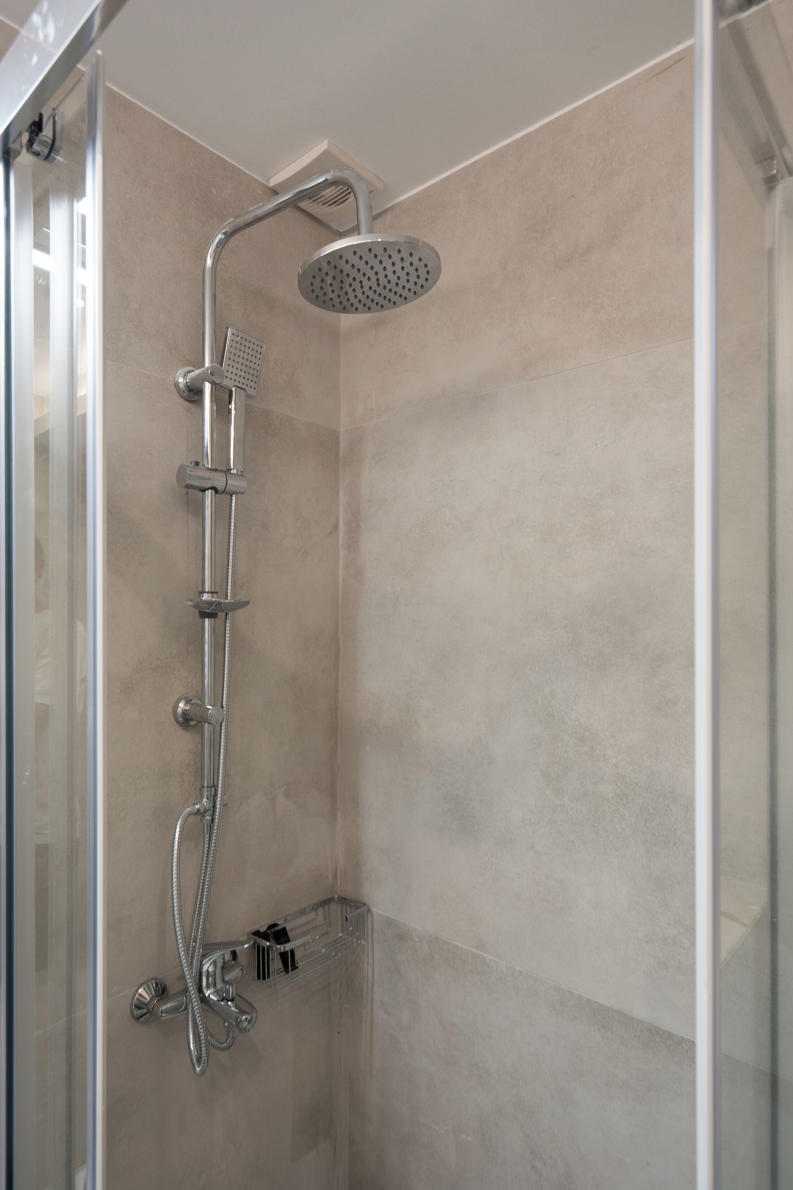 A modern shower with a handheld showerhead, a fixed showerhead, and a rain showerhead.