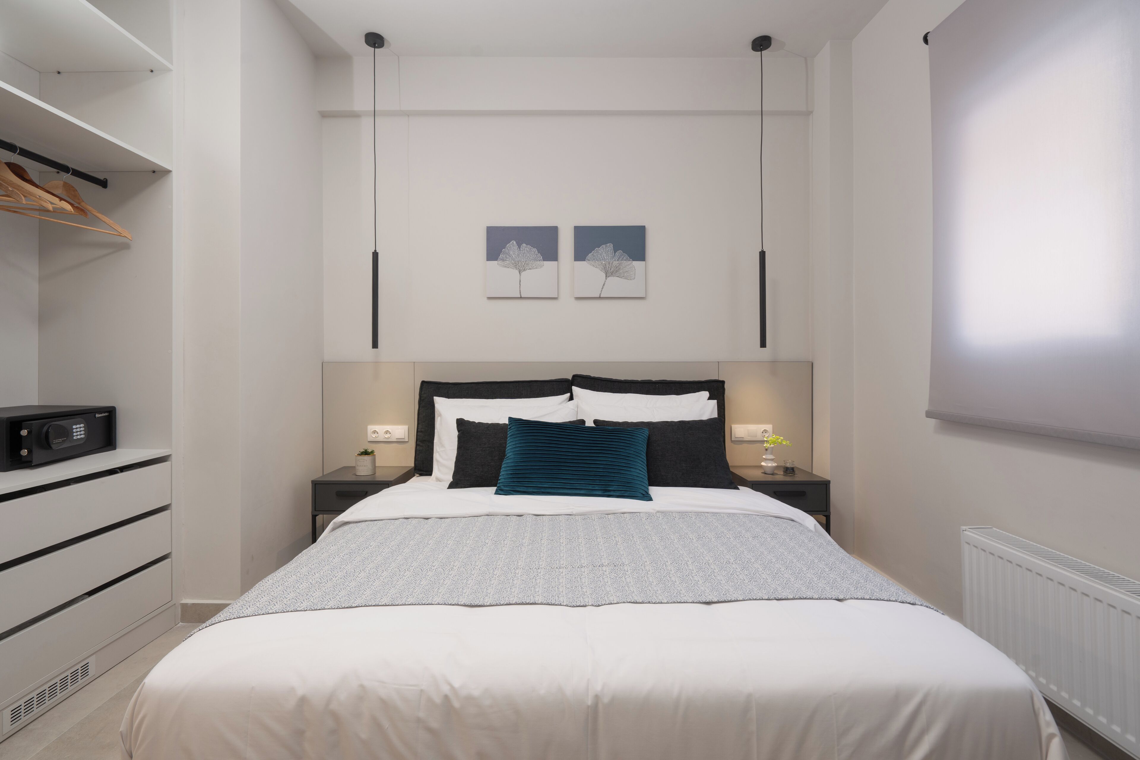 A modern bedroom with a neatly made bed, a bedside table with a lamp, and a wardrobe.