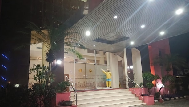 A hotel entrance with a statue, steps, and potted plants.