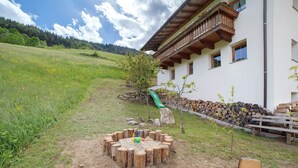 Un espace extérieur rustique aménagé avec une table ronde en bois, un petit arbre et un bâtiment doté d’un balcon.