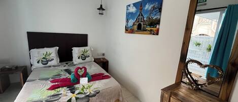 A neatly arranged hotel room with a bed, a nightstand, a wooden bench, a painting, and a mirror.