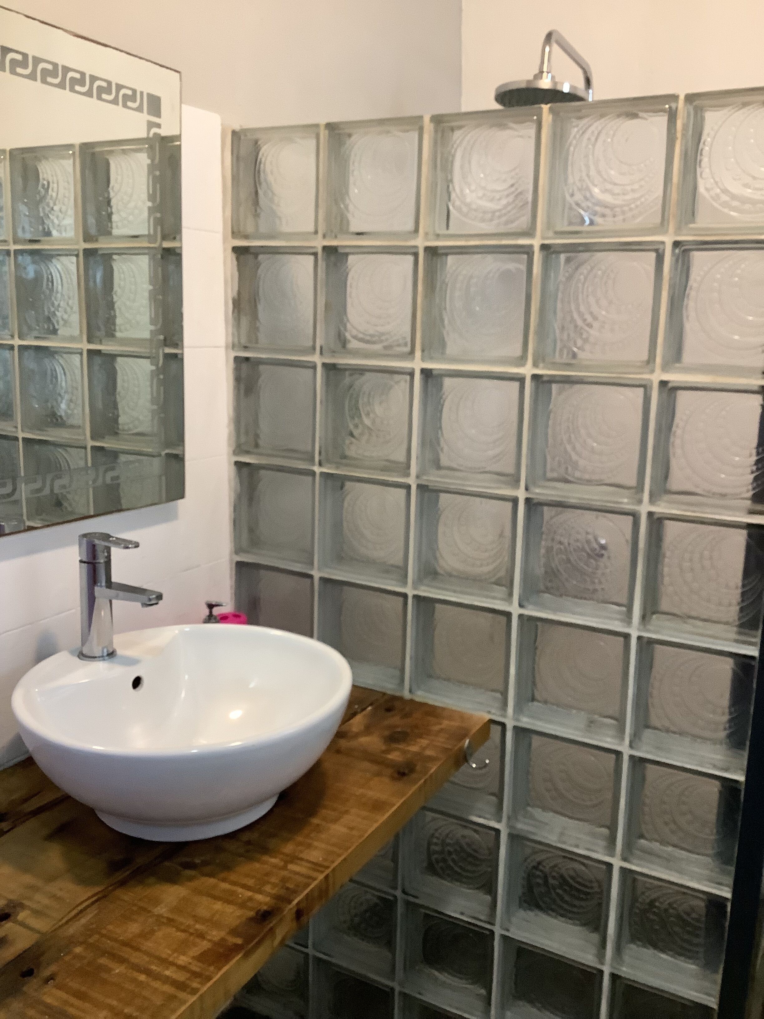 A bathroom with a white sink, a mirror, and a shower with frosted glass panels.