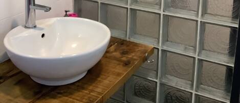 A bathroom with a white sink, a mirror, and a shower with frosted glass panels.