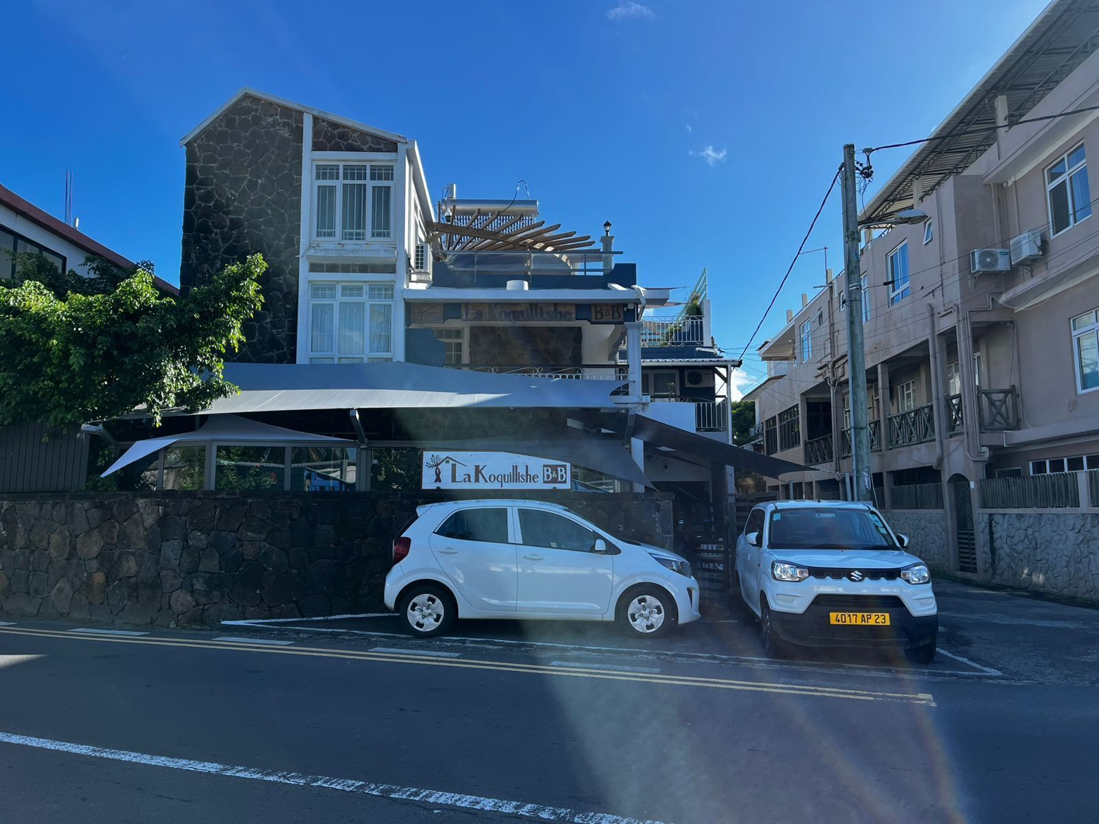 Un edificio con un letrero que dice "La Koquillishe B&B" y un coche blanco estacionado al frente.
