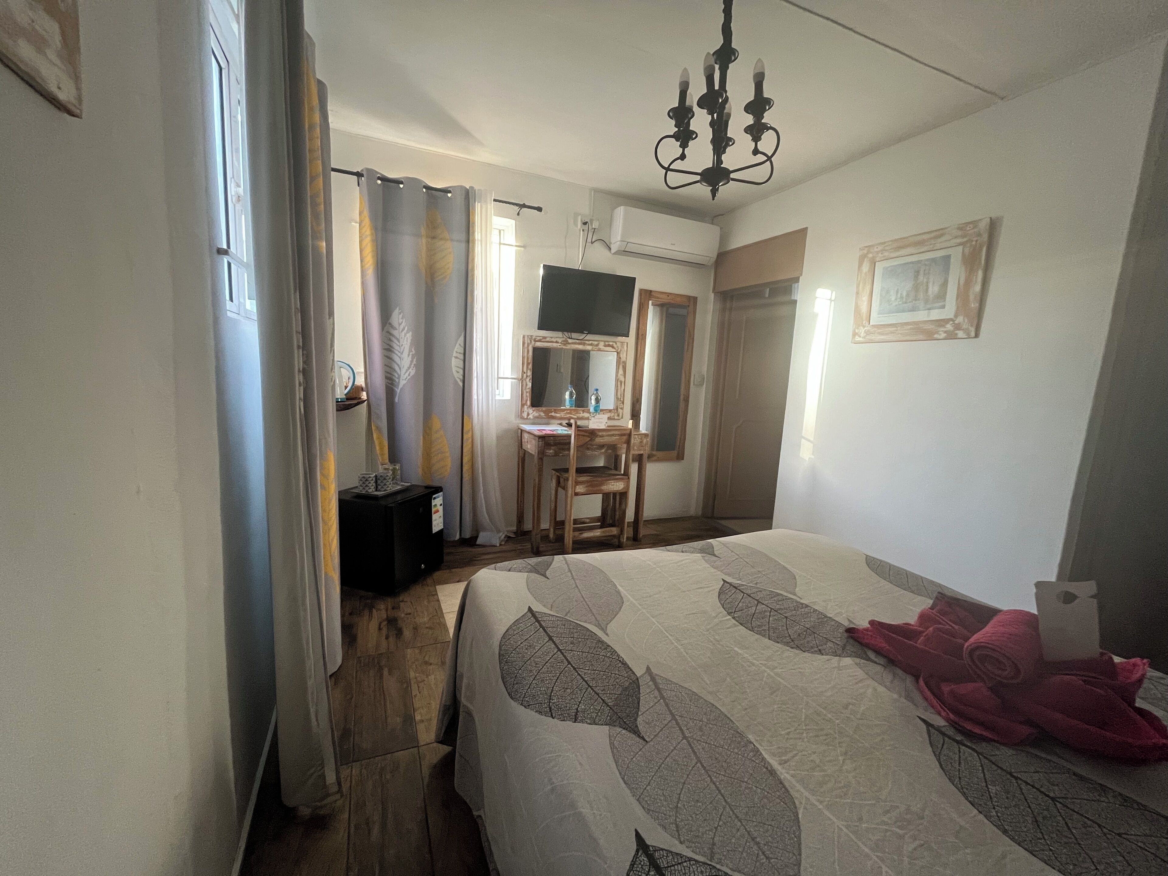 Ein Schlafzimmer mit Bett, Schreibtisch, Stuhl, Spiegel und einer Chandelier.