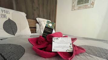 Un lit bien fait, avec un oreiller orné d’un motif de feuille, un livre intitulé « La Kaguillishe » et une carte de bienvenue.