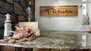 Une enseigne en bois sur laquelle est inscrit « La Koquillishe », un phare décoratif, un certificat d’appréciation et une grande coquille sur un comptoir en bois.