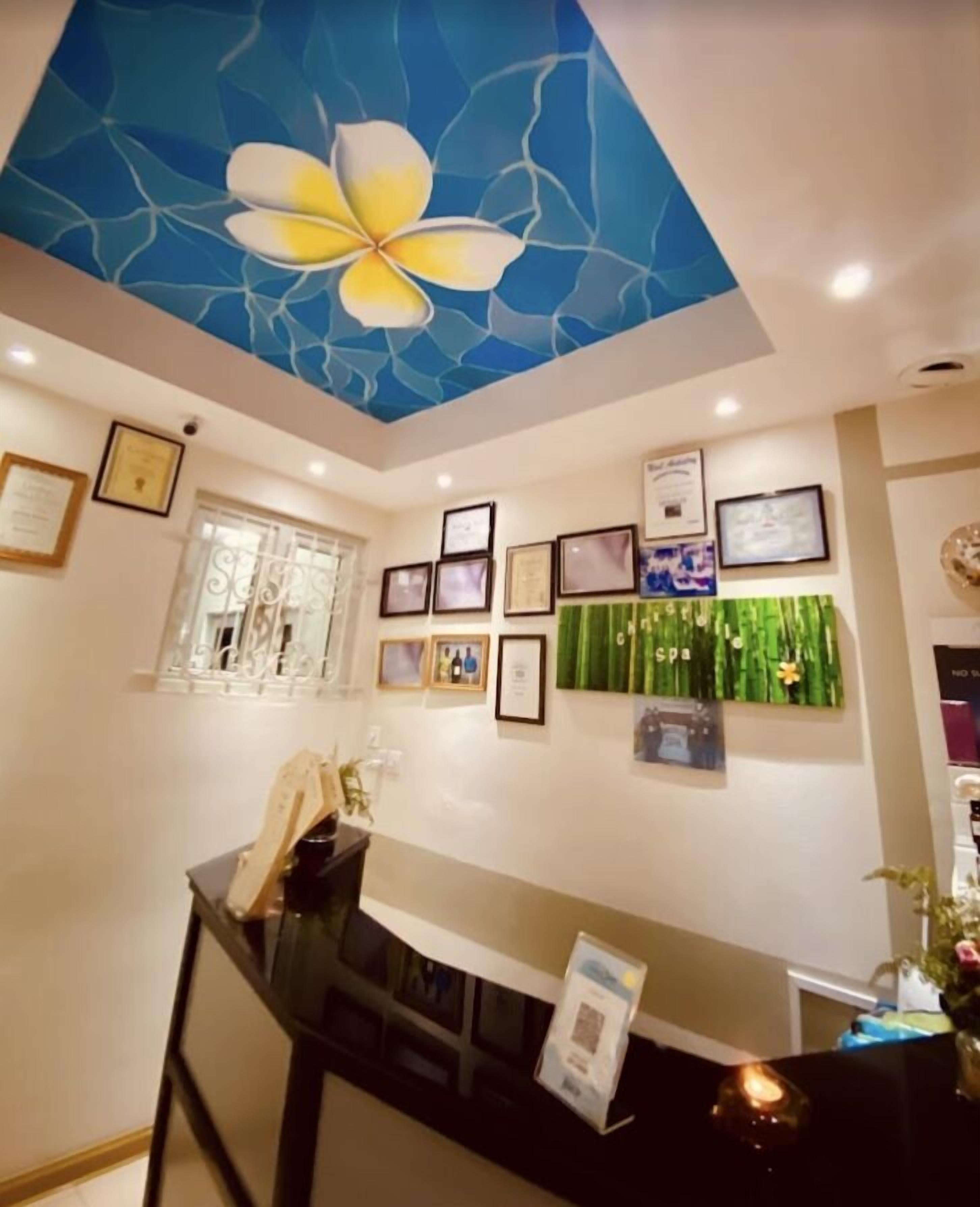 A reception area with a ceiling mural, framed certificates, and a reception desk.