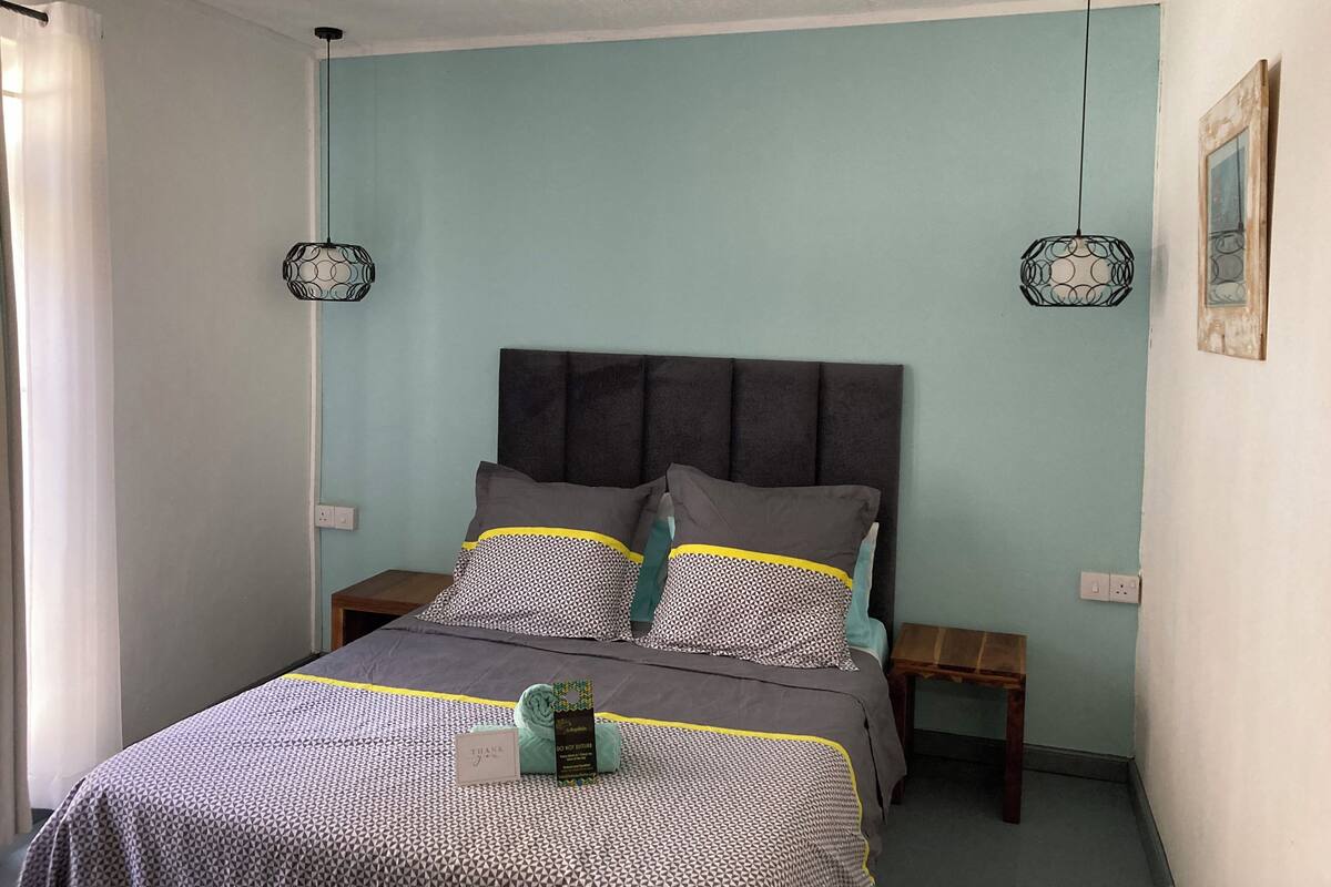 A neatly made bed with patterned bedding, two bedside tables, and decorative wall lamps.