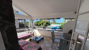 Un balcon avec deux lits, une table et une chaise.