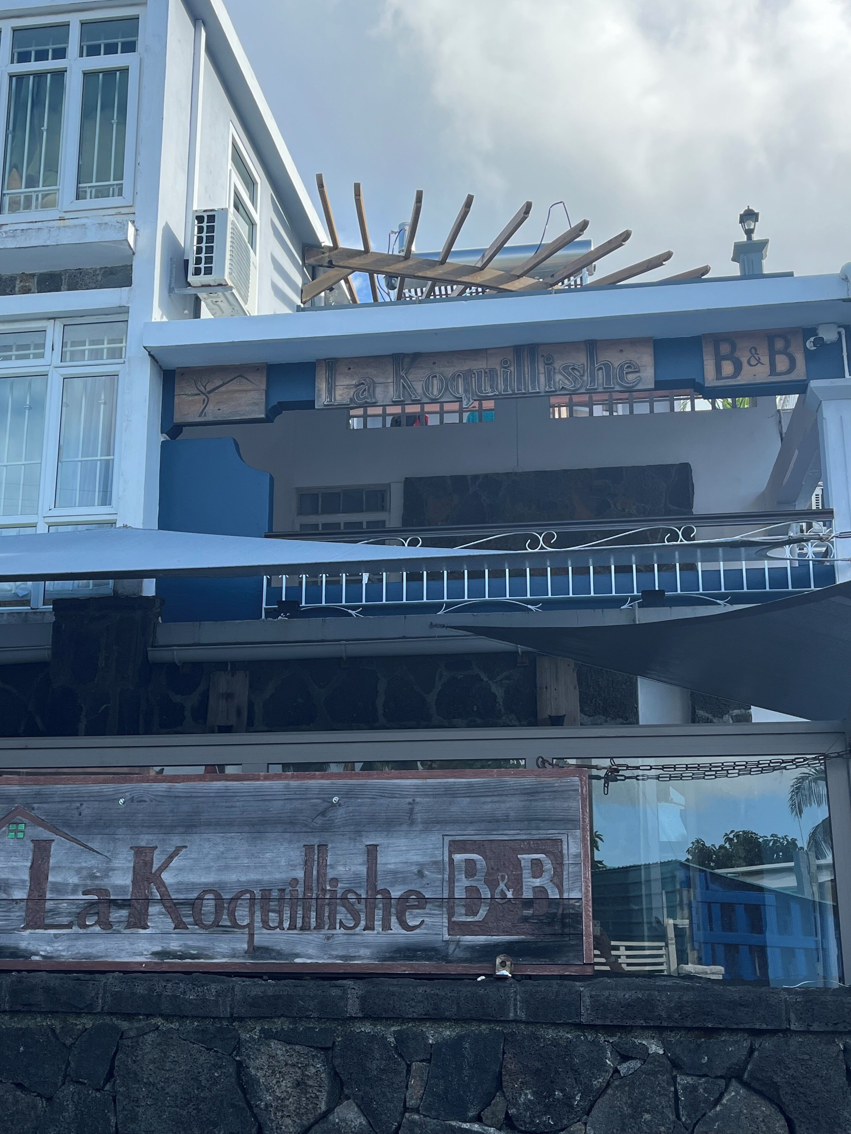 A building with a sign reading "La Koquillishe B&B" and a wooden structure above it.
