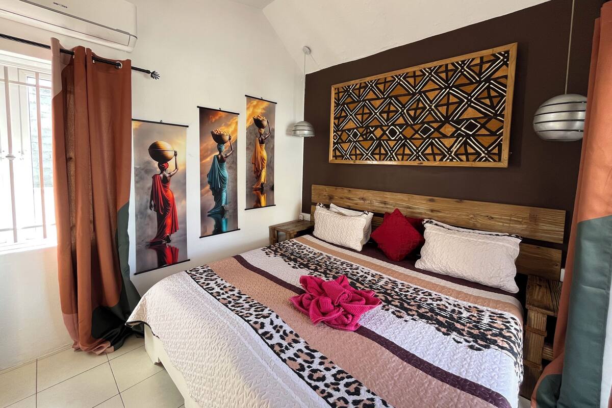 A bedroom with a large bed, a wooden headboard, and three wall-mounted artworks.