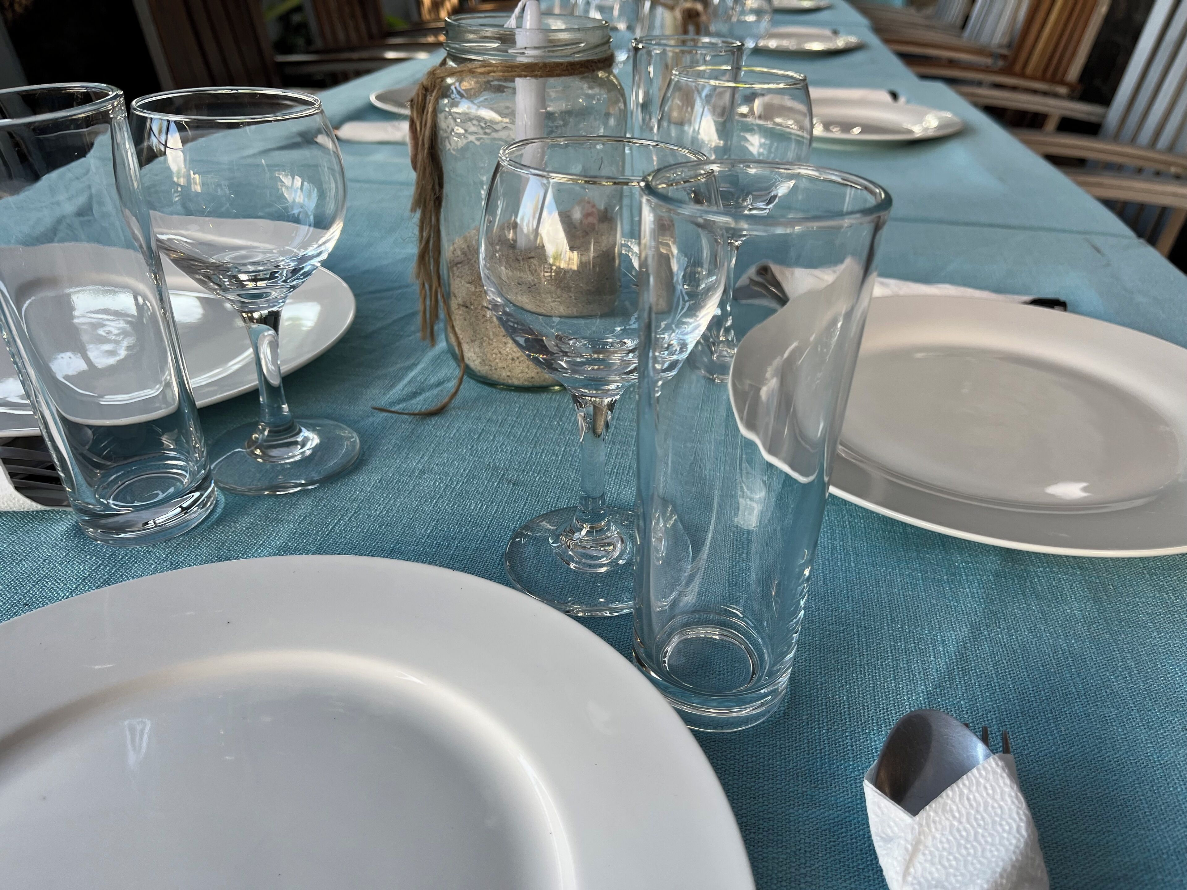 Une table dressée avec de la vaisselle transparente et des assiettes blanches, probablement préparée pour un repas.