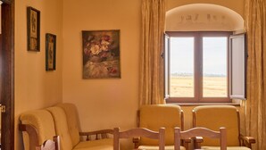 A room with a dining table, two yellow armchairs, a painting on the wall, and a window with curtains. - Apartment 'Amapola' with Balcony, Wi-Fi and Air Conditioning (Valsequillo)