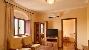 A living room with a television, wooden furniture, a cabinet, and a window with curtains. - Apartment 'Amapola' with Balcony, Wi-Fi and Air Conditioning (Valsequillo)