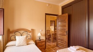 A hotel room with a bed, bedside table, lamp, and a wooden wardrobe. - Apartment 'Amapola' with Balcony, Wi-Fi and Air Conditioning (Valsequillo)