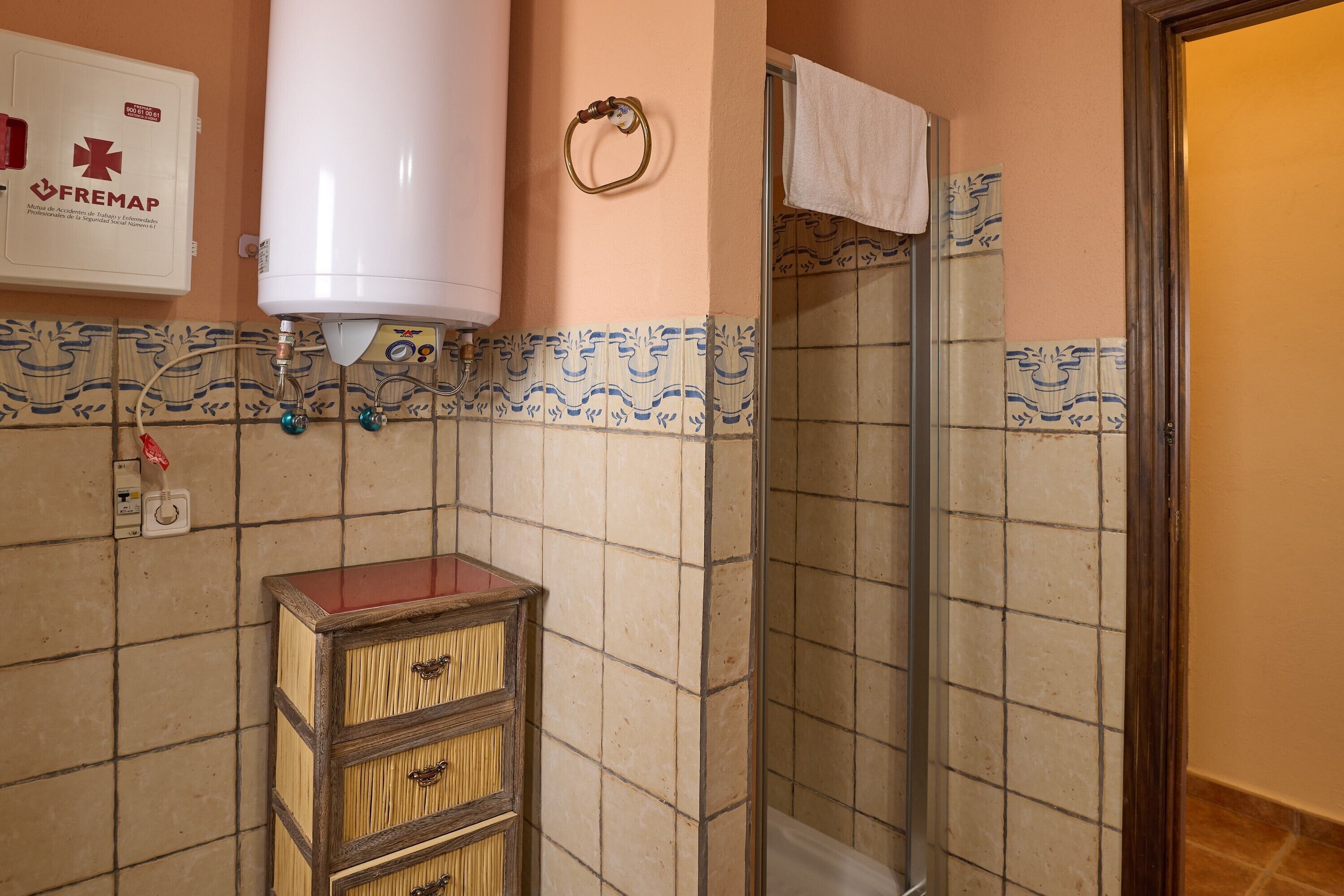 Un baño con ducha, inodoro, toallero y calentador de agua.