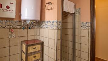 Un baño con ducha, inodoro, toallero y calentador de agua.