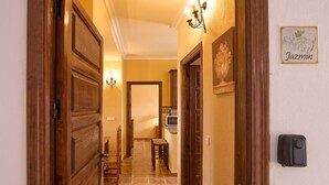 A hallway with wooden doors, a dining area, a kitchen, and a wall-mounted light fixture. - Apartment 'Jazmin' with Balcony, Wi-Fi and Air Conditioning (Valsequillo)