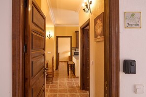 A hallway with wooden doors, a dining area, a kitchen, and a wall-mounted light fixture.