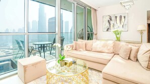 Un salon moderne doté d’une grande baie vitrée, d’un canapé beige, d’une table basse en verre et offrant une vue sur la ville.