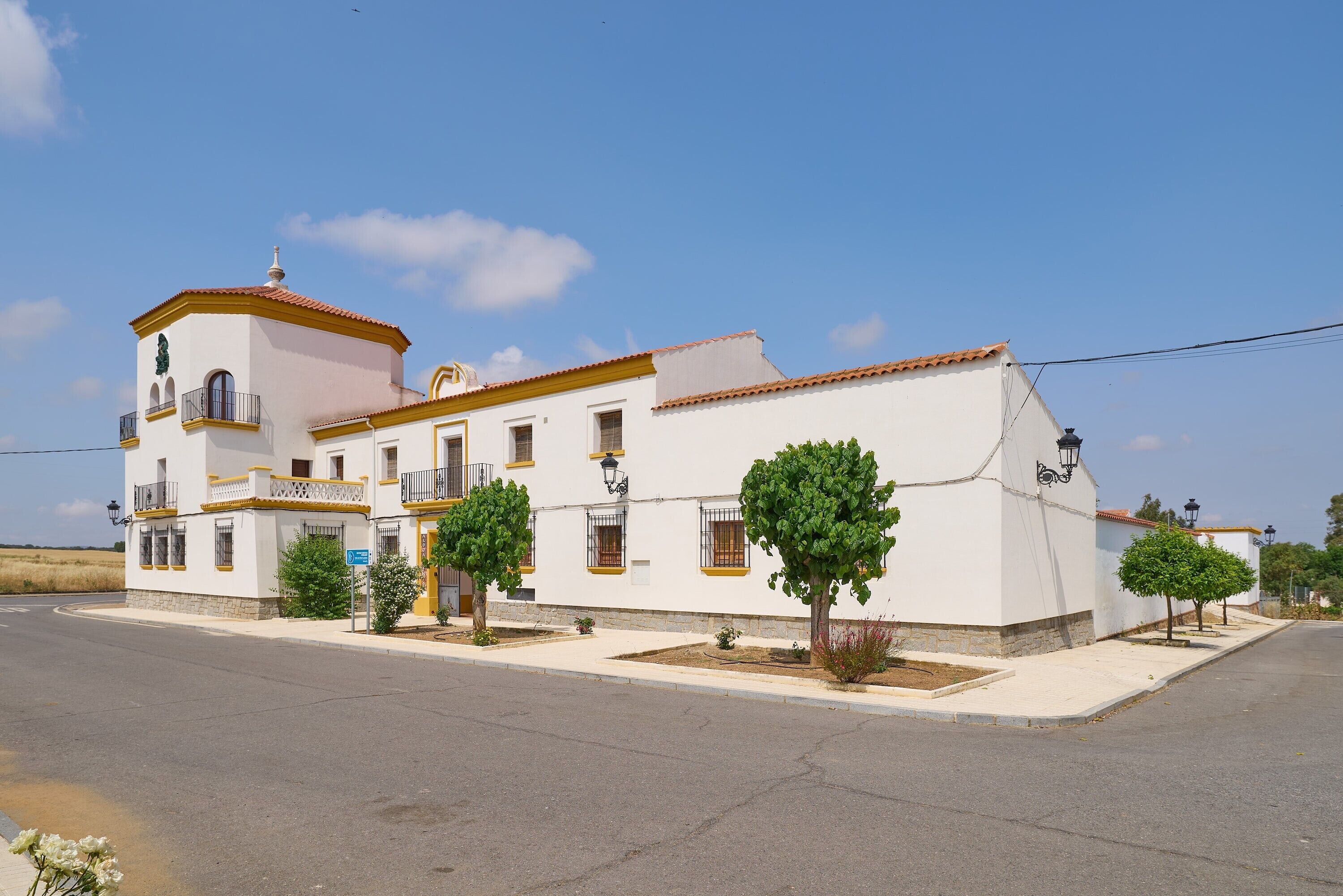 Un edificio blanco con una torre, varias ventanas y una calle pavimentada.