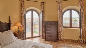 Une chambre à coucher avec un lit, une commode et deux fenêtres avec des rideaux.